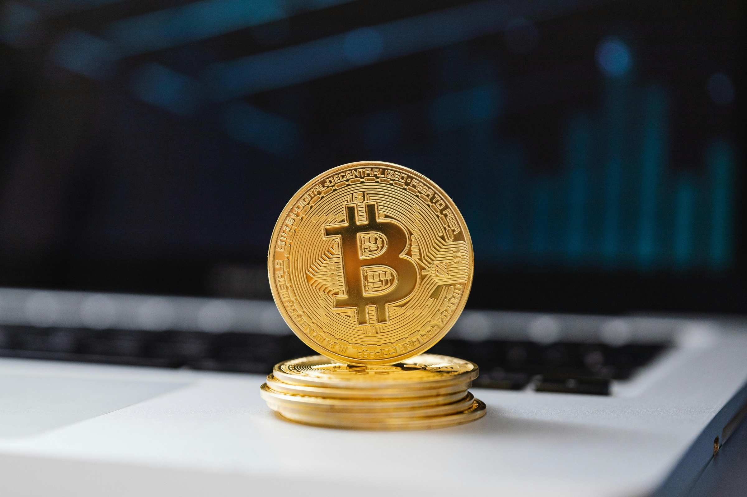 Stack of gold Bitcoin coins on a laptop with a blurred background